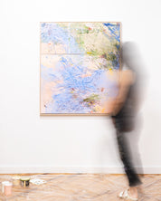 Abstract painting on a white wall with a blurred person in the foreground