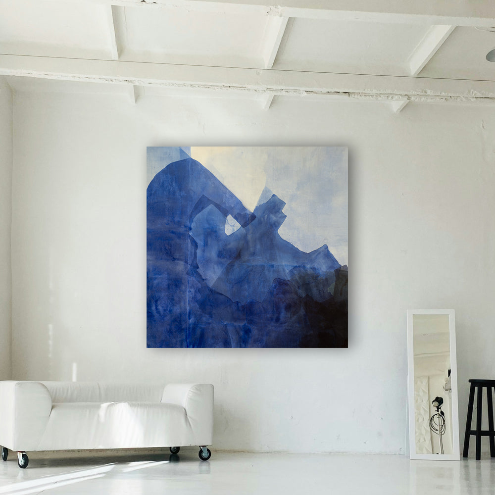 A large blue and white painting hangs on a white wall above a white couch