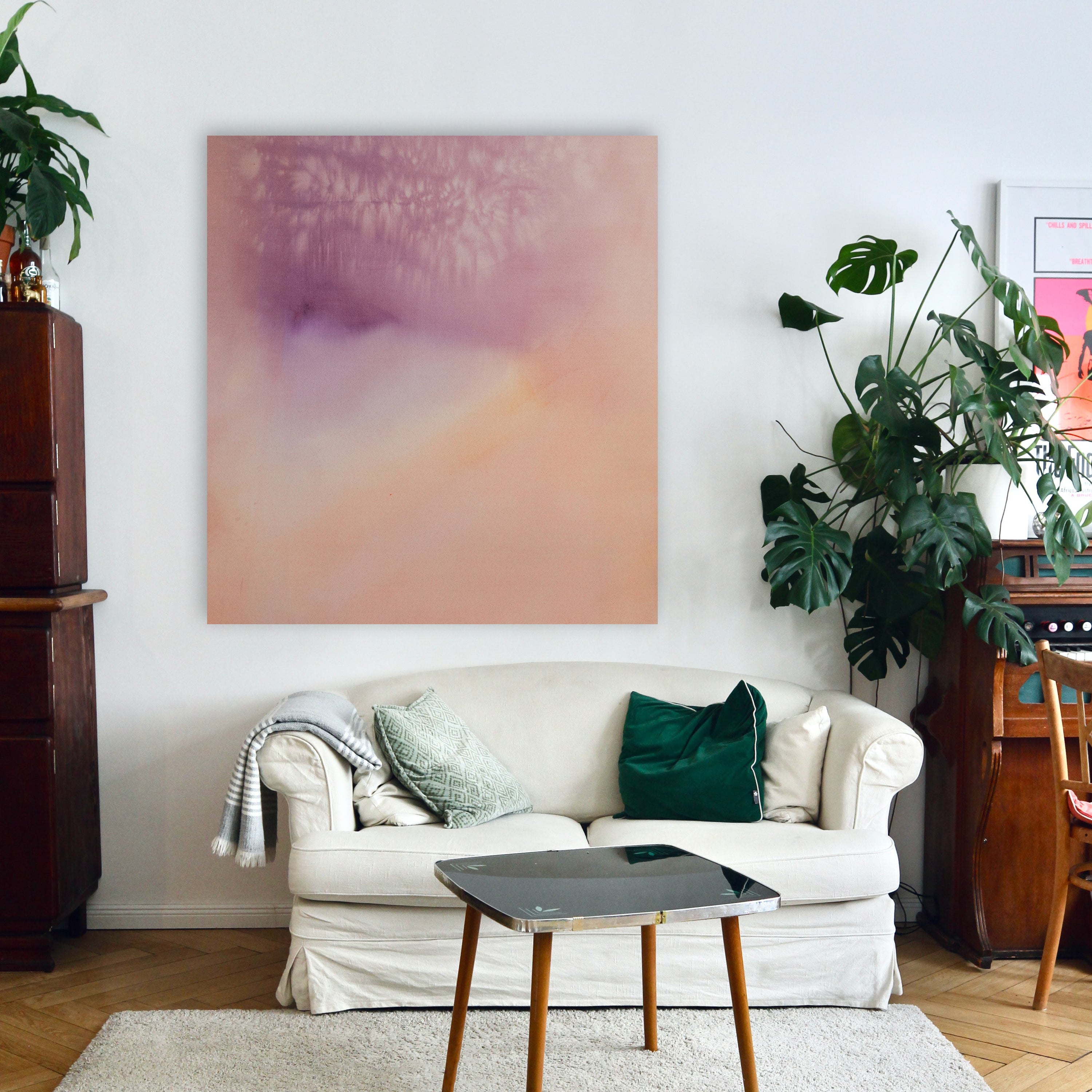 Large purple and pale orange abstract painting hangs about a white loveseat in a living room.